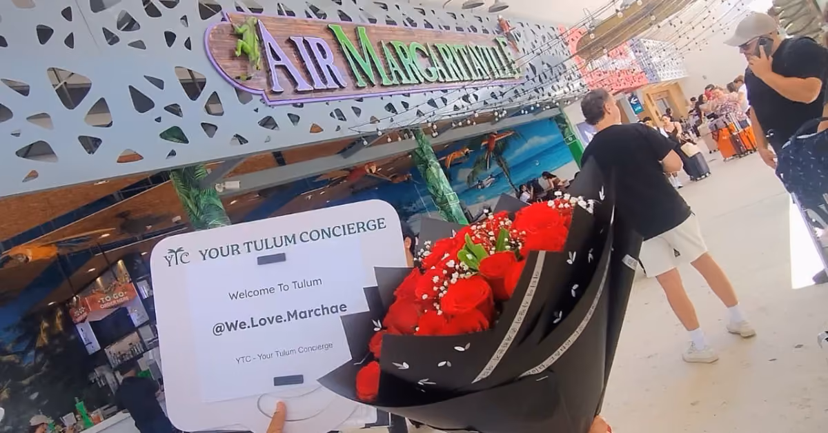 A Your Tulum Concierge welcome sign and a bouquet of red roses waiting for guests at the airport