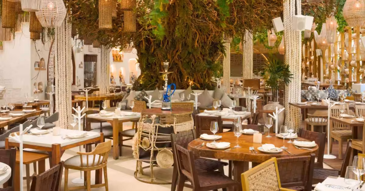 The dining room of Ilios Tulum, white tables under hanging plants