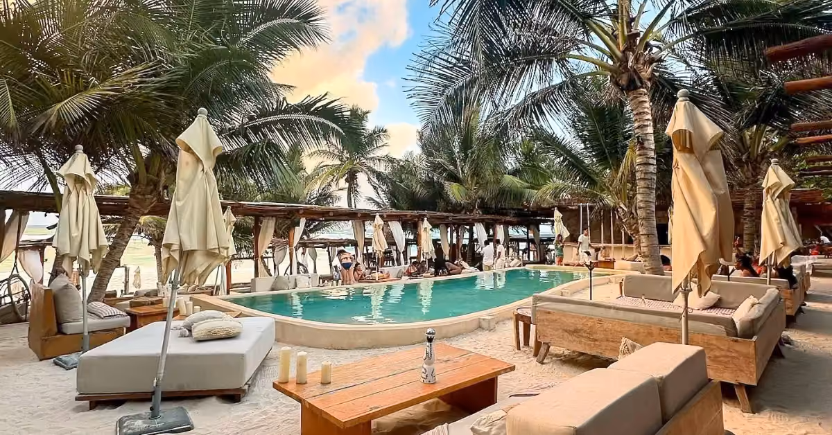 The pool at Tantra Beach Club, with daybeds under the palm trees