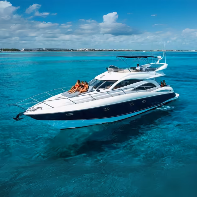 A white and blue yacht with people relaxing on deck cruises on turquoise water beneath a partly cloudy sky, another boat behind.