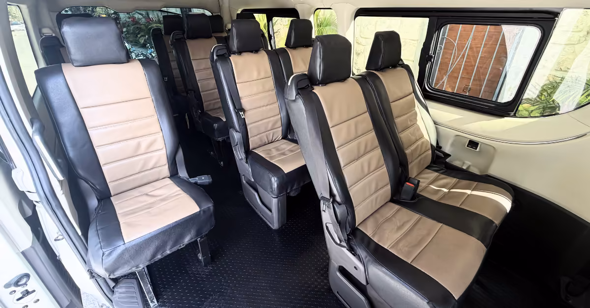 Minivan interior with three rows of black and beige leather seats facing forward; clean, spacious, and neatly arranged.