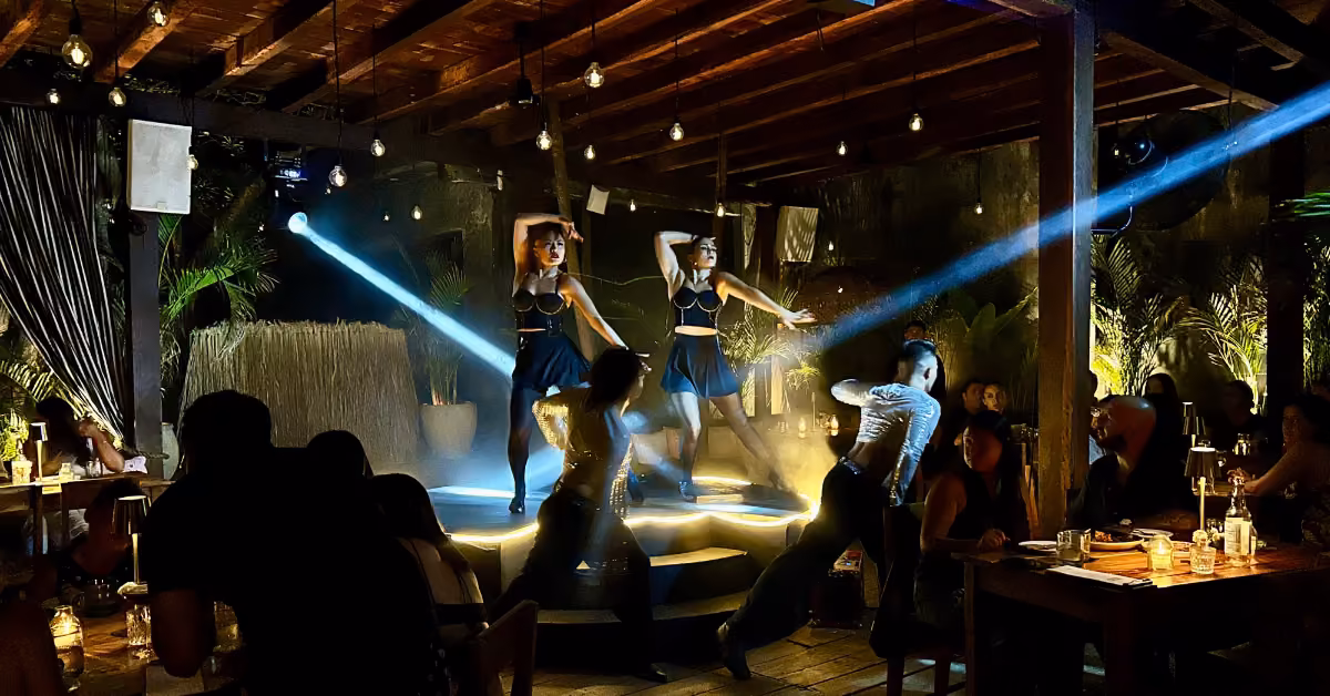 Two female dancers perform under spotlights at Gitano Jungle Restaurant as guests watch and dine around the dimly lit stage.