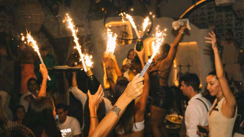 Guests raise bottles with sparklers in the Ilios dining room