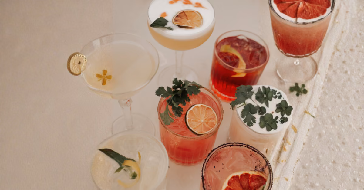 Colorful cocktails in assorted glasses, garnished with citrus and herbs, arranged on a light surface at Panamera Rooftop.