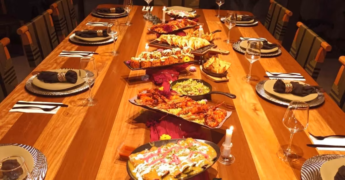 Elegant wooden table for eight with wine glasses and napkins, filled with colorful appetizers, mains, and salads.