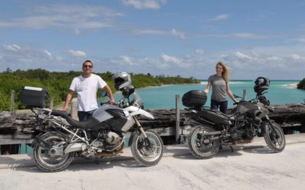 two people posing with their motorcycles at the sian kaan bridge close to tulum
