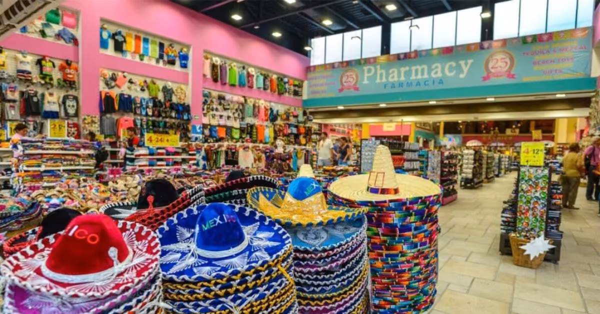 Vibrant shop with stacks of sombreros, hats, and souvenirs. Shelves hold clothes, bags, flags; Pharmacy sign overhead.