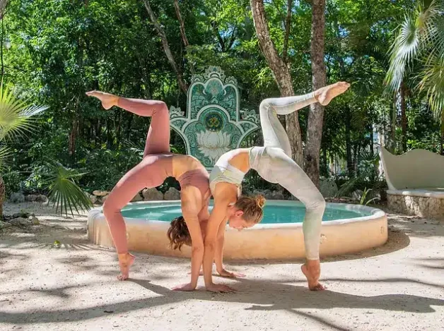 Where to do yoga in Tulum: two girls doing a yoga pose together at Holistika
