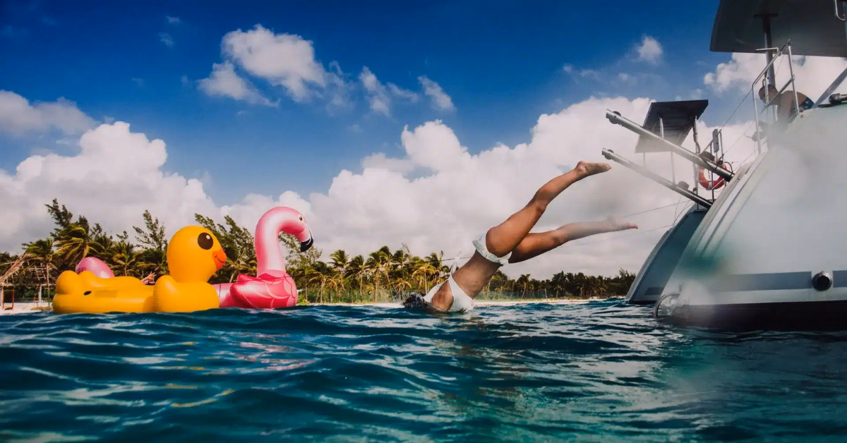 a girl jumping of a boat near tulum